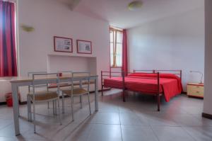 um quarto com uma cama vermelha, uma mesa e cadeiras em Il Seicento em Sernio