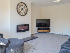 a living room with a tv and a clock on the wall at Park Lane in Auldgirth