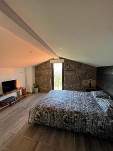 a bedroom with a large bed with a stone wall at Casas do Monte in Resende