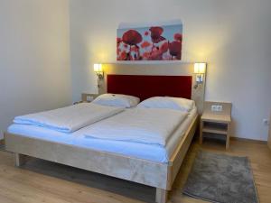 Schlafzimmer mit einem großen Bett mit einem roten Kopfteil in der Unterkunft Pension Peterhof in Mörbisch am See