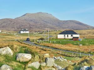 a house on a road with a mountain in the background at Padraigs Cottage in Howmore