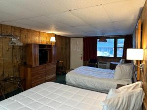 a hotel room with two beds and a television at Maple Leaf Inn Lake Placid in Lake Placid