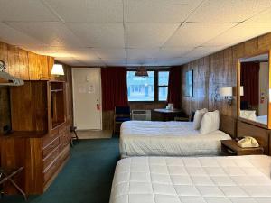 a hotel room with two beds and a desk at Maple Leaf Inn Lake Placid in Lake Placid