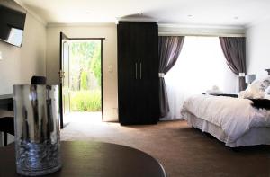 ein Hotelzimmer mit einem Bett, einem Tisch und einem Fenster in der Unterkunft La Coscello Guest House in Edenvale