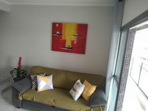 un sofá en una sala de estar con una pintura en la pared en Apartamento Guarujá Astúrias en Guarujá