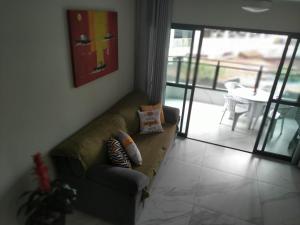 uma sala de estar com um sofá com almofadas em Apartamento Guarujá Astúrias no Guarujá