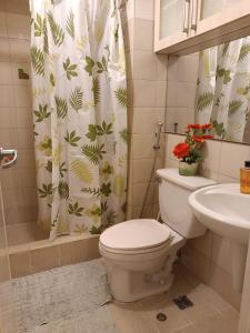 a bathroom with a toilet and a sink and a shower curtain at WestParc Cedar Alabang in Manila