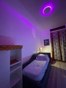 1 dormitorio con 1 cama con luz morada en el techo en R’nB&B, en Milán