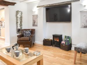 a living room with a chair and a fireplace at Thornton Cottage in Grizebeck