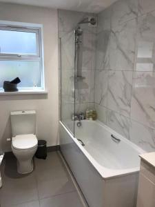 a bathroom with a tub and a toilet and a shower at Ella Court Devon in Torquay
