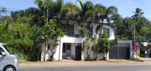 um edifício branco com árvores em frente em Saragama Holiday Resort em Kurunegala