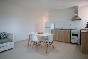 a kitchen with a white table and white chairs at Cabaña 1920 - frente a viñedo in San Rafael