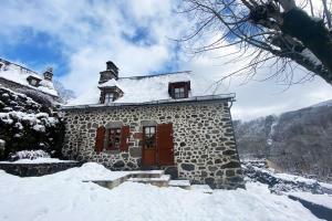 un edificio de piedra con nieve en el costado en Le Gite des Montagnes - Saint Projet de Salers, en Saint-Projet-de-Salers
