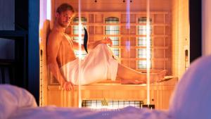 a man sitting on a bed in a cage at Apartamenty SPA z prywatnym Jacuzzi & Sauną in Białystok
