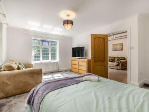 a bedroom with a bed and a couch and a television at Greenacre in Fawkham