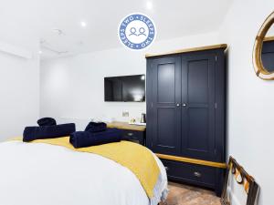 a bedroom with a bed and a black cabinet at Driftwood Boutique Guest House in Rhosneigr