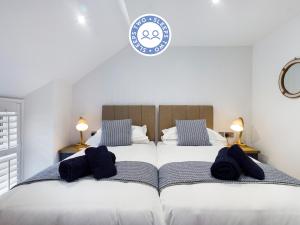 a bedroom with two beds with black pillows on them at Driftwood Boutique Guest House in Rhosneigr