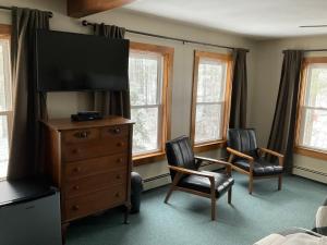 LovellにあるThe Lodge at Pleasant Pointのベッドルーム1室(ドレッサー、テレビ、椅子2脚付)