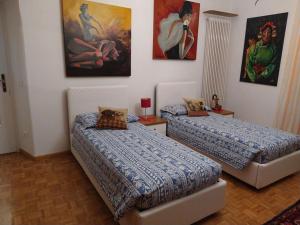 2 camas en una habitación con pinturas en la pared en AppartamentoMonika con parcheggio privato - Volano, en Volano