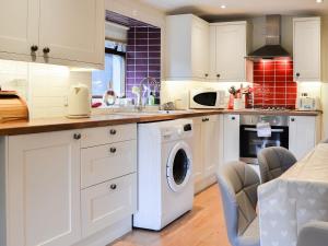 a kitchen with white cabinets and a washer and dryer at Y Bwthyn in Llandegai