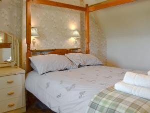 a bedroom with a bed with a wooden frame and a mirror at Y Bwthyn in Llandegai