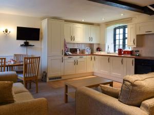 a kitchen with white cabinets and a living room at Knowle Cottage in Colaton Raleigh