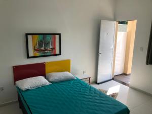 a bedroom with a bed with a blue comforter and a refrigerator at Kitnet Maitinga in Bertioga