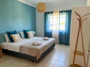 um quarto com uma cama com paredes azuis e uma janela em Herdade da Vagem em Rogil