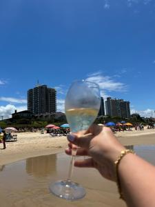 uma mulher segurando um copo de vinho em frente à praia em Apartamento Dona Elvira em Piçarras