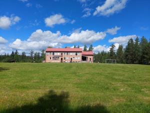 a large building in a field with a field of grass at Hotell Nederhögen Vildmarkscenter in Rätan