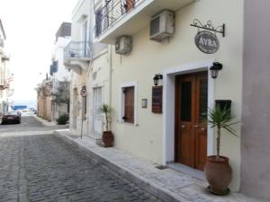 a cobblestone street in front of a white building with two potted plants at Avra Rooms in Ermoupoli