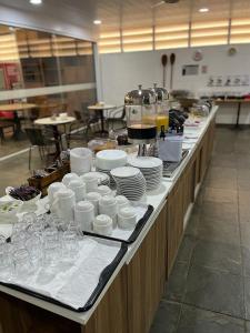 una línea de buffet con platos, tazas y vasos en Bravo Suites São Carlos, en São Carlos