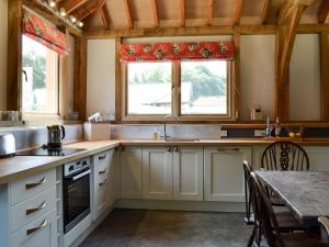 une cuisine avec des placards blancs, une table et une fenêtre dans l'établissement Little Barn - Ukc2539, à Fordingbridge