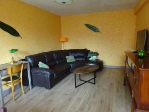 sala de estar con sofá de cuero negro y mesa en La Cerisaie, en Ferreux