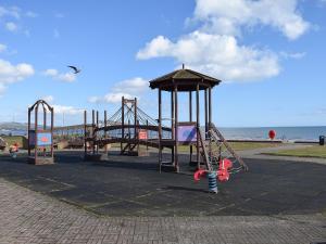 a playground with a slide and a swing set on the beach at Bramble Cottage in Leven-Fife