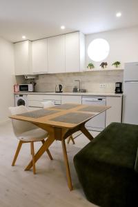 a kitchen with a wooden table and white cabinets at Canto dos Poetas in Leiria