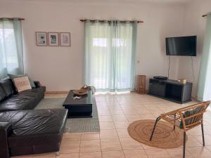ein Wohnzimmer mit einem Sofa und einem TV in der Unterkunft Herdade da Vagem in Rogil