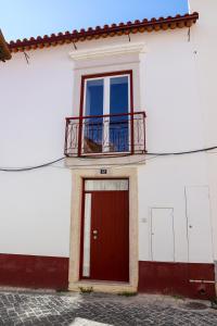 ein weißes Gebäude mit einer roten Tür und einem Balkon in der Unterkunft Canto dos Poetas in Leiria