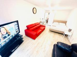 a living room with a red couch and a flat screen tv at Extra Large Double one Bedroom Rental Near Central London & Close to Transport in London