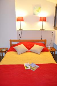 1 cama con manta roja y amarilla y 2 lámparas en VVF Haute Loire Saint-Julien-Chapteuil, en Saint-Julien-Chapteuil