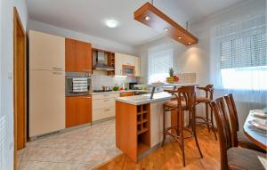 a kitchen with wooden cabinets and a kitchen island with bar stools at Stunning Home In Senkovec With Sauna in Slakovec