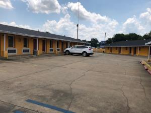 a white car parked in front of a yellow building at Ranch House Motel Marksville in Marksville