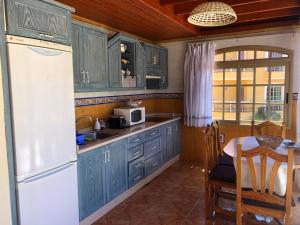 a kitchen with blue cabinets and a white refrigerator at Atlantida Deluxe penthouse by Apartamentos Estrella del Norte in Icod de los Vinos