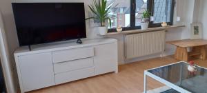 ein Wohnzimmer mit einem Flachbild-TV auf einer weißen Kommode in der Unterkunft To feel good: Quiet apartment, between Köln and Düsseldorf in a 3-family house in Leverkusen