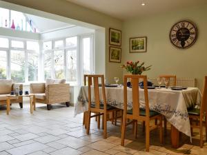 a dining room with a table with chairs and a clock at Three Ways in Stroud