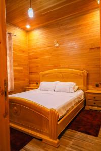 Cama en habitación con pared de madera en Hôtel les truites en Imouzzer du Kandar