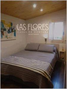 Dormitorio con cama con las palabras "Las flores caesar de normania" en Las Flores, casa del cerro en Potrerillos