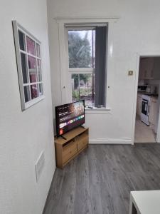 a living room with a flat screen tv on a wooden stand at A home away from home in Birmingham