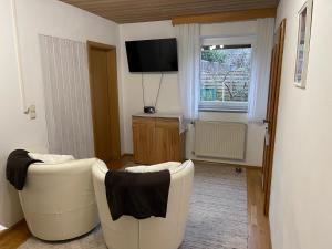 ein Wohnzimmer mit 2 weißen Stühlen und einem TV in der Unterkunft Ferienwohnungen Gmeiner in Bad Endorf