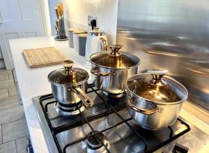 four pots sitting on top of a stove in a kitchen at City Link - Mapperley Park Suite - Free parking,tram&busroutes,HSwifi,upto9 by KP in Nottingham